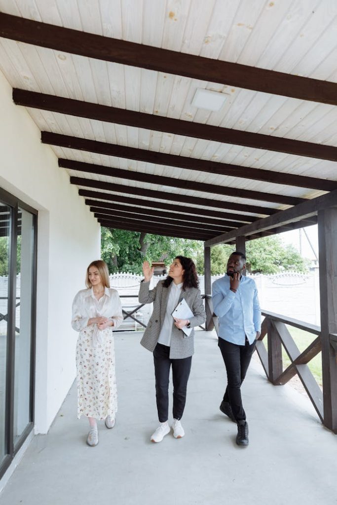 people-with-real-estate-agent-on-porch-8469939 Real estate agent showing house to clients during walk-through on a porch.
