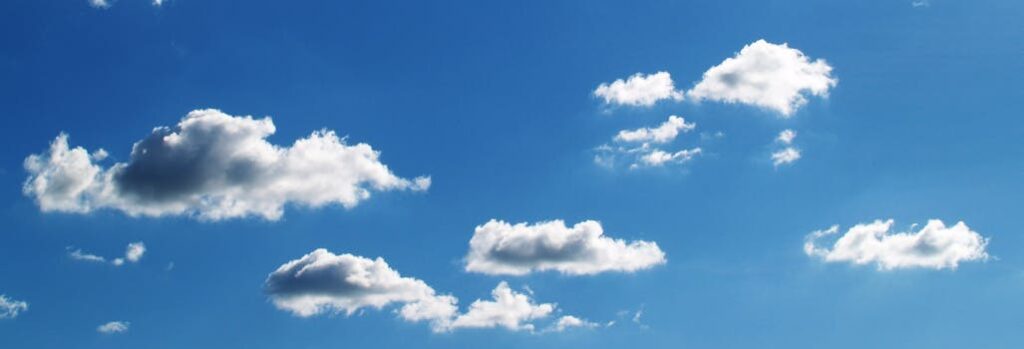 Peaceful blue sky filled with fluffy white clouds on a sunny day.