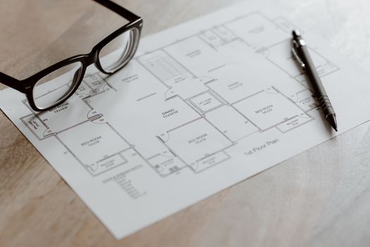 pexels-photo-4792507-4792507 Composition von plan von room and black pen with eyeglasses placed on wooden table at daytime